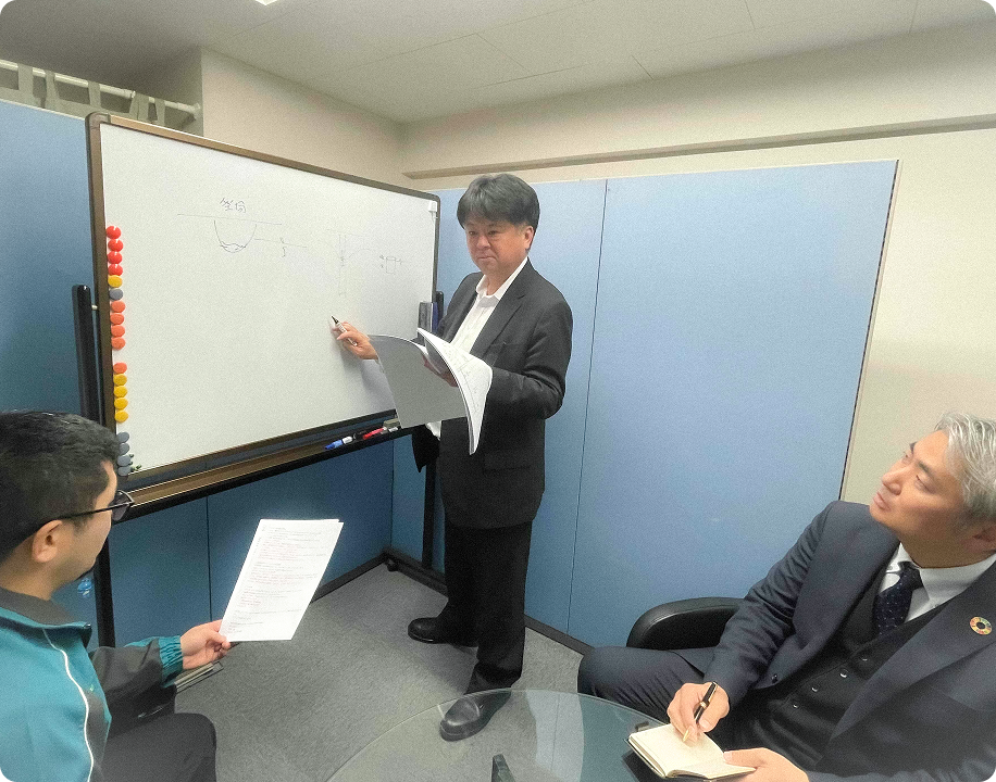 オフィスにて3名のスタッフが真剣に議論を行っている様子
